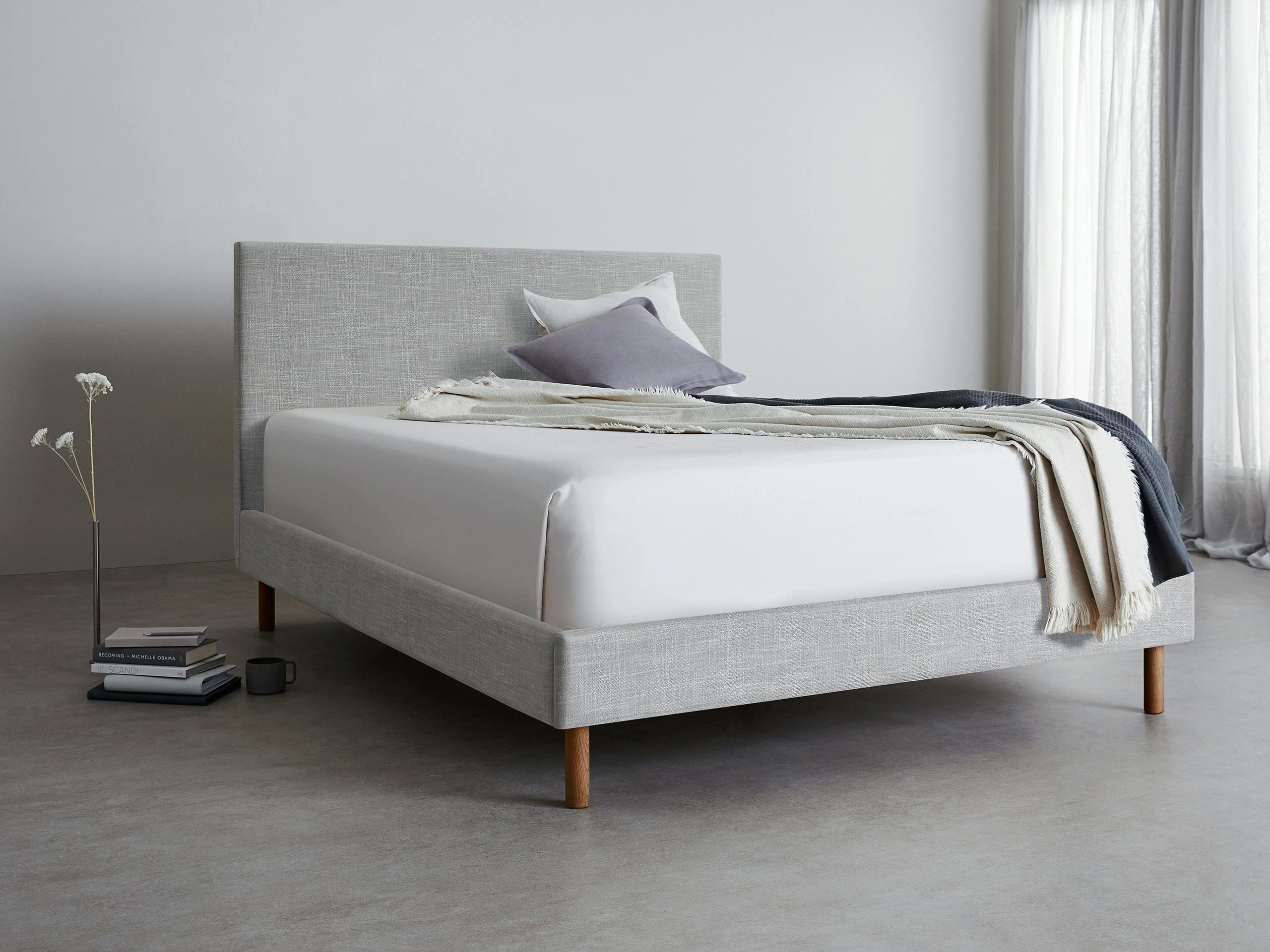 A light grey SD Indestruct Bed bed frame in a three quarter view with a mattress and throw.